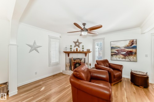Living area featuring light wood-finish flooring, white walls, and a ceiling fan - 11115 44 Street, Edmonton, AB - Indoor Photo Showing Living Room With Fireplace