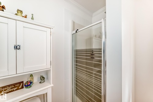 Enclosed shower with a framed glass door, white wall tiling, and a built-in white cabinet with storage - 11115 44 Street, Edmonton, AB - Indoor