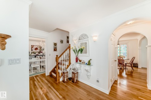 Bright entryway featuring wood-finish flooring, a wood staircase with white balusters, and white crown molding - 11115 44 Street, Edmonton, AB - Indoor Photo Showing Other Room