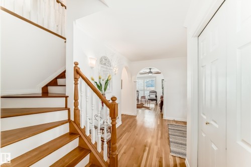 Hardwood flooring throughout the entry, a staircase with wooden treads and a white baluster, and arched doorways define this interior space - 11115 44 Street, Edmonton, AB - Indoor Photo Showing Other Room