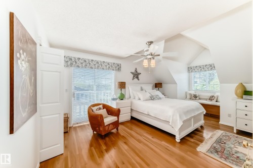 Bright room featuring rich wood-finish flooring, a ceiling fan with integrated lighting, and a built-in window bench - 11115 44 Street, Edmonton, AB - Indoor Photo Showing Bedroom