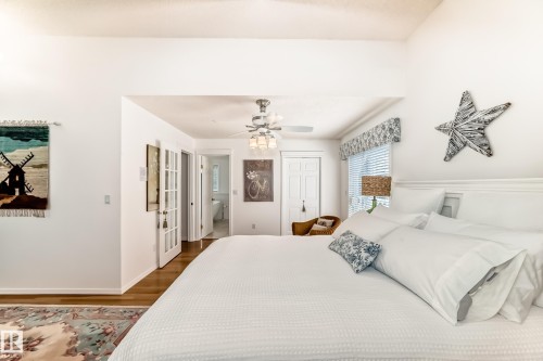 Spacious room featuring wood-finish flooring, a ceiling fan with integrated lighting, and a white paneled headboard - 11115 44 Street, Edmonton, AB - Indoor Photo Showing Bedroom