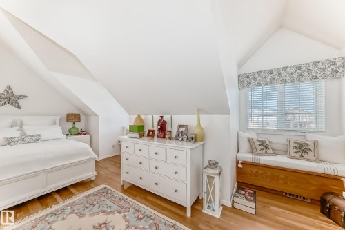 Angled ceilings define this bright room, featuring wood-finish flooring - 11115 44 Street, Edmonton, AB - Indoor Photo Showing Bedroom