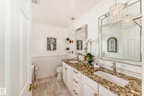 Dual vanity featuring a granite countertop with undermount sinks, flanked by elegant framed mirrors - 11115 44 Street, Edmonton, AB - Indoor Photo Showing Bathroom