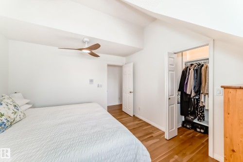 Bright bedroom featuring wood-finish flooring, a modern ceiling fan with integrated lighting, and a closet with bifold doors - 11115 44 Street, Edmonton, AB - Indoor Photo Showing Bedroom