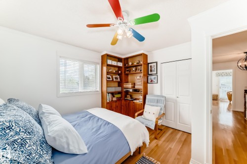 Bright room featuring wood-finish flooring, a white ceiling fan, and a window with white blinds - 11115 44 Street, Edmonton, AB - Indoor Photo Showing Bedroom