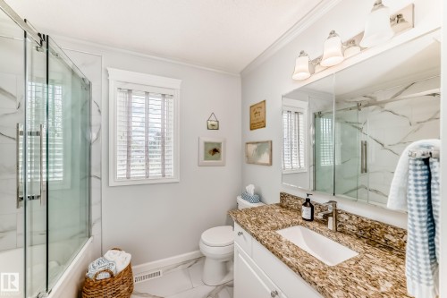 Bathroom featuring a white vanity with a granite countertop, undermount sink, and chrome faucet - 11115 44 Street, Edmonton, AB - Indoor Photo Showing Bathroom