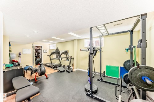 Dedicated fitness area featuring durable rubber flooring, recessed lighting, and a power rack - 11115 44 Street, Edmonton, AB - Indoor Photo Showing Gym Room