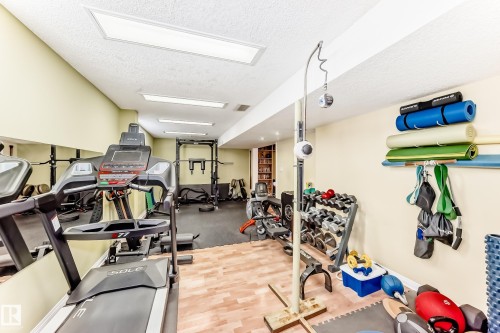 Dedicated exercise space featuring recessed lighting, a mirrored wall, and a combination of wood-finish and rubber flooring - 11115 44 Street, Edmonton, AB - Indoor Photo Showing Gym Room