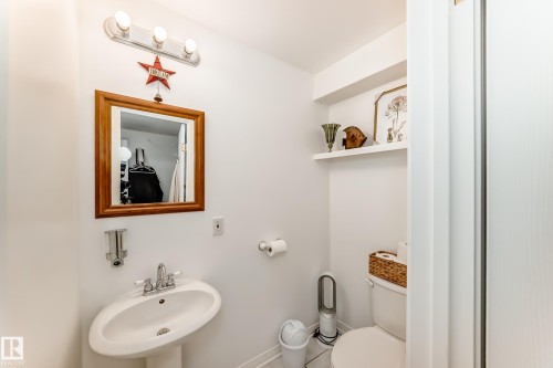 Pedestal sink with chrome faucet, framed mirror, and wall-mounted light fixture - 11115 44 Street, Edmonton, AB - Indoor Photo Showing Bathroom