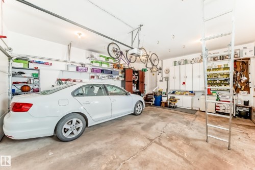 Concrete floor garage with overhead door tracks, white wall cabinetry, and built-in shelving - 11115 44 Street, Edmonton, AB - Indoor Photo Showing Garage