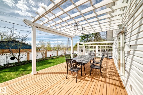 Expansive wood-finish deck with a white pergola, offering an outdoor living space alongside a manicured lawn - 11115 44 Street, Edmonton, AB - Outdoor With Deck Patio Veranda