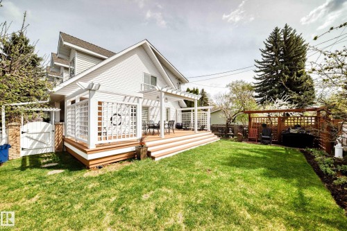 Expansive backyard with a manicured lawn, a multi-level wood-finish deck with white lattice and pergola features, and mature perimeter trees - 11115 44 Street, Edmonton, AB - Outdoor With Deck Patio Veranda