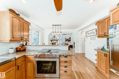 Kitchen featuring stainless steel range, wood-finish cabinetry, granite-style countertops, and white tile backsplash - 11115 44 Street, Edmonton, AB - Indoor Photo Showing Kitchen
