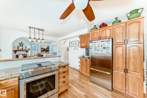 Kitchen featuring wood-finish flooring, light wood cabinetry, stainless steel appliances, and granite-style countertops - 11115 44 Street, Edmonton, AB - Indoor Photo Showing Kitchen
