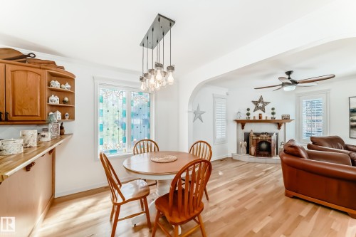 Open-concept living space featuring wood-finish flooring, a decorative fireplace, and an arched entryway - 11115 44 Street, Edmonton, AB - Indoor With Fireplace