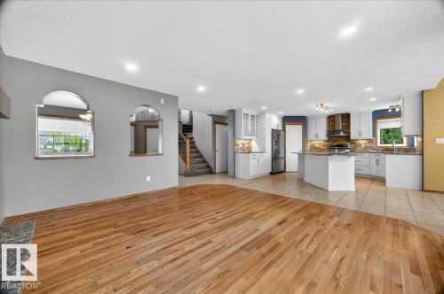Open-concept living area featuring hardwood flooring, recessed lighting, and a modern kitchen with light cabinetry, stainless steel appliances, and a central island - 11824 13 Avenue, Edmonton, AB - Indoor Photo Showing Kitchen