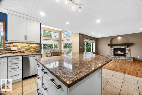 Kitchen island with a polished countertop and built-in cabinetry - 11824 13 Avenue, Edmonton, AB - Indoor Photo Showing Kitchen With Upgraded Kitchen