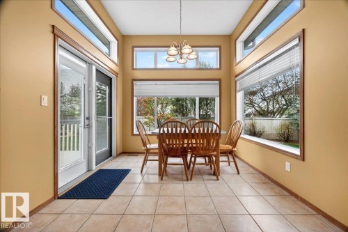 Dining area featuring expansive windows, transom windows, ceramic tile flooring, and a glass-paneled patio door with an integrated screen - 11824 13 Avenue, Edmonton, AB - Indoor