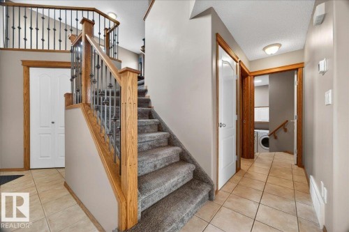 Foyer featuring a grand staircase with wood newel posts, handrails, and wrought iron balusters - 11824 13 Avenue, Edmonton, AB - Indoor Photo Showing Other Room