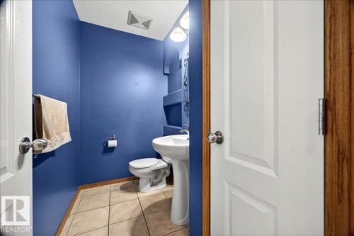 Powder room featuring a pedestal sink, white toilet, and tile flooring - 11824 13 Avenue, Edmonton, AB - Indoor Photo Showing Bathroom