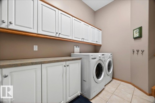 Utility space featuring extensive upper and lower white cabinetry, a neutral countertop, tiled flooring, and a neutral wall color - 11824 13 Avenue, Edmonton, AB - Indoor Photo Showing Laundry Room