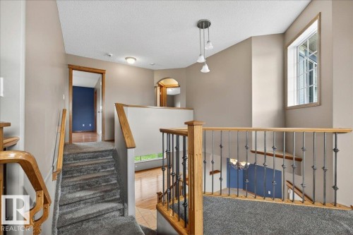 Upper-level landing with carpeted stairs, wood railings, and wrought-iron balusters - 11824 13 Avenue, Edmonton, AB - Indoor Photo Showing Other Room