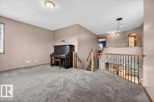 Spacious upper-level landing featuring neutral carpet, a wood and wrought iron staircase railing, and recessed ceiling lighting - 11824 13 Avenue, Edmonton, AB - Indoor Photo Showing Other Room