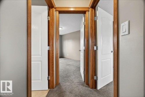 Interior doorway with wood-finish trim and white paneled doors - 11824 13 Avenue, Edmonton, AB - Indoor Photo Showing Other Room