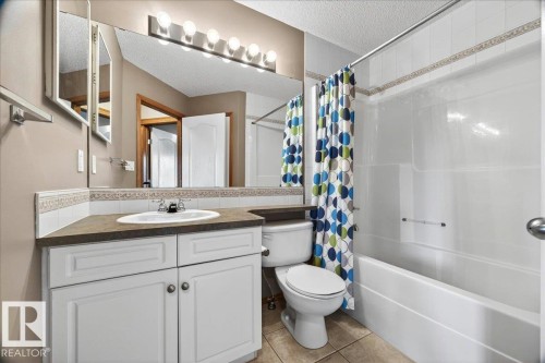 Bathroom featuring a white vanity with cabinet storage, a built-in sink, and a dark countertop - 11824 13 Avenue, Edmonton, AB - Indoor Photo Showing Bathroom