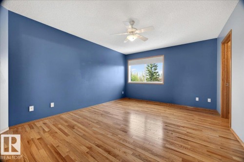 Spacious room featuring wood-finish flooring, a ceiling fan with integrated lighting, and a window providing natural light - 11824 13 Avenue, Edmonton, AB - Indoor Photo Showing Other Room