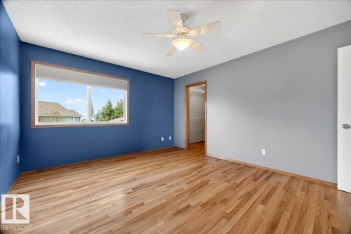 Spacious room featuring wood-finish flooring, a large window with wood trim, and a ceiling fan with integrated lighting - 11824 13 Avenue, Edmonton, AB - Indoor Photo Showing Other Room