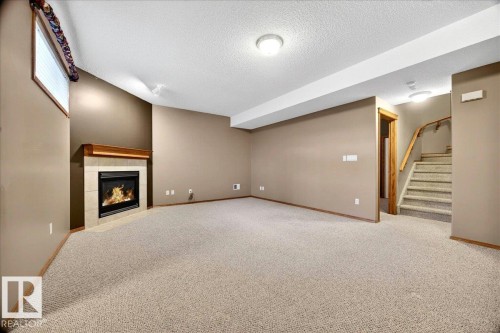 Spacious room featuring a corner fireplace with a tiled surround and wood mantel - 11824 13 Avenue, Edmonton, AB - Indoor With Fireplace