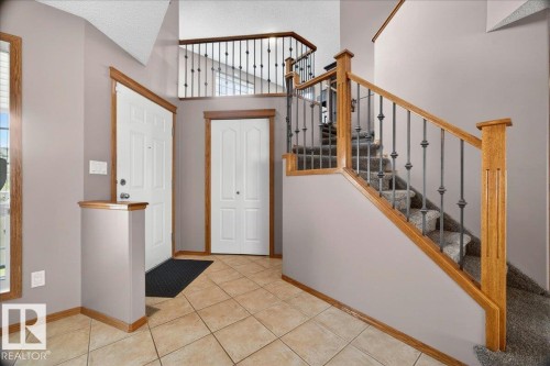 Foyer featuring tile flooring, a staircase with wood-finish handrails and decorative metal balusters, and a second-story landing with matching railing - 11824 13 Avenue, Edmonton, AB - Indoor Photo Showing Other Room