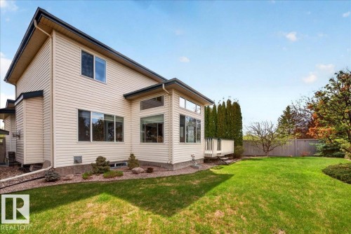 Rear exterior featuring light-toned horizontal siding, multiple windows, and a raised deck with white railing - 11824 13 Avenue, Edmonton, AB - Outdoor