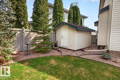 Backyard featuring a shed with vinyl siding, shingled roof, and white door - 11824 13 Avenue, Edmonton, AB - Outdoor With Exterior
