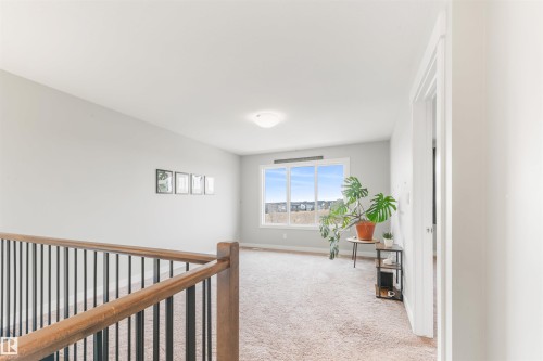This spacious open-concept area features carpet flooring, light gray walls, and a large window offering expansive views - 607 40 Street Sw, Edmonton, AB - Indoor Photo Showing Other Room
