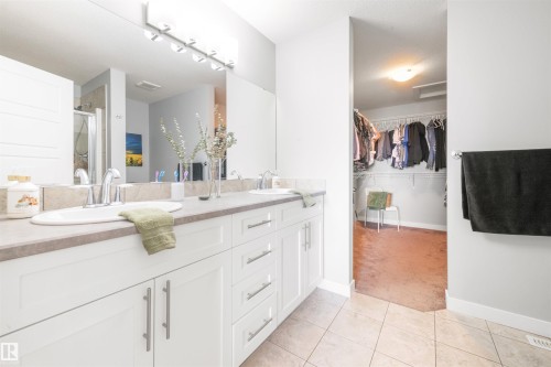 Bathroom featuring a double vanity with white cabinetry, light countertops, and a large mirror - 607 40 Street Sw, Edmonton, AB - Indoor Photo Showing Bathroom