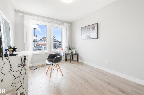 This room features light-colored walls, light wood flooring, and two large windows offering views of the surrounding neighborhood - 607 40 Street Sw, Edmonton, AB - Indoor