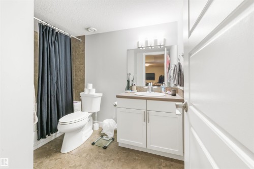 Bathroom featuring a white vanity with a rectangular sink, a mirrored medicine cabinet, a toilet, and tiled flooring - 607 40 Street Sw, Edmonton, AB - Indoor Photo Showing Bathroom