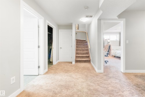 Carpeted hallway with a staircase featuring a wooden handrail - 607 40 Street Sw, Edmonton, AB - Indoor Photo Showing Other Room