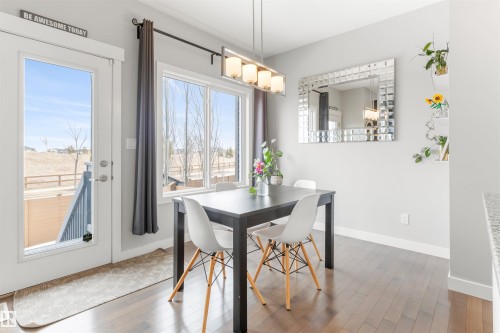 Dining area featuring hardwood floors, a modern chandelier, and a large window providing natural light - 607 40 Street Sw, Edmonton, AB - Indoor Photo Showing Dining Room