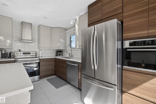 Modern kitchen featuring stainless steel appliances, two-tone cabinetry, white subway tile backsplash, white countertops, and recessed lighting - 15251 88A Street, Edmonton, AB - Indoor Photo Showing Kitchen