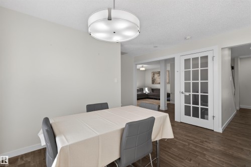 Dining area featuring wood-finish flooring, a contemporary drum chandelier, and a white French pane door - 15251 88A Street, Edmonton, AB - Indoor Photo Showing Dining Room