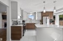 Modern kitchen featuring a central island, white subway tile backsplash, stainless steel appliances, and two-tone cabinetry with wood-finish and high-gloss white elements - 15251 88A Street, Edmonton, AB  - Indoor Photo Showing Kitchen With Upgraded Kitchen 