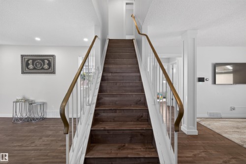 Staircase featuring wood-finish treads and risers, white balusters, and a brass-tone handrail - 15251 88A Street, Edmonton, AB - Indoor Photo Showing Other Room