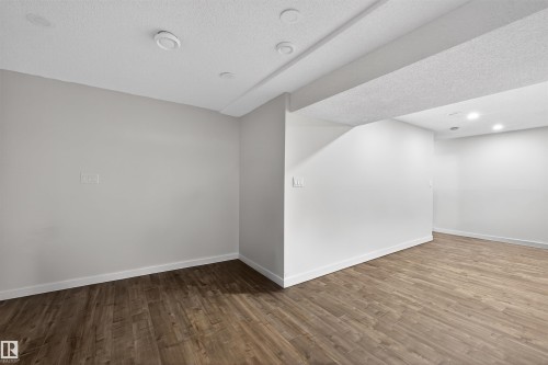 Spacious room featuring wood-finish flooring, white baseboards, light gray walls, white ceilings, and recessed lighting - 15251 88A Street, Edmonton, AB - Indoor Photo Showing Other Room