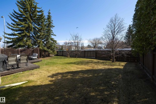 Spacious backyard featuring a large lawn, a multi-level wood deck, mature evergreen trees, and perimeter fencing - 15251 88A Street, Edmonton, AB - Outdoor With Backyard