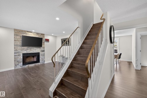 Staircase featuring wood-finish treads, a contrasting white and brass railing, and recessed lighting - 15251 88A Street, Edmonton, AB - Indoor With Fireplace