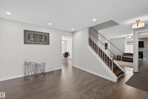 Hardwood-finish flooring extends throughout this entry area, featuring a staircase with white risers and a dark wood-finish tread - 15251 88A Street, Edmonton, AB - Indoor